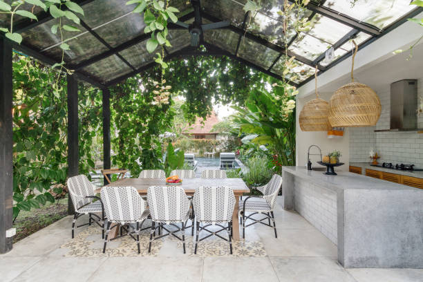 Outdoor kitchen Open kitchen with empty dining room table and chairs outside, against green fresh plants on background